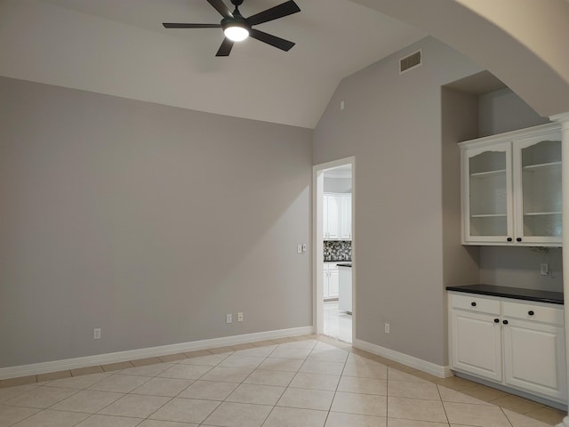 tiled empty room featuring vaulted ceiling and ceiling fan