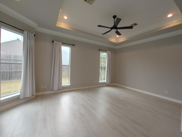 spare room featuring ornamental molding, light wood-type flooring, ceiling fan, and a tray ceiling