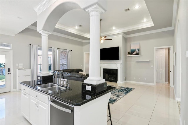 kitchen with sink, a kitchen island with sink, white cabinetry, decorative columns, and light tile patterned flooring