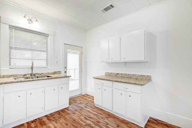 3500 32nd St, Port Arthur, TX 77642 - kitchen with light wood-style floors, white cabinetry, crown molding, and light stone counters
