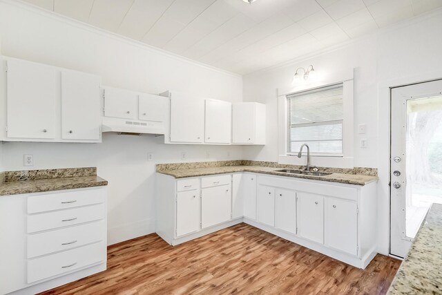 3500 32nd St, Port Arthur, TX 77642 - kitchen featuring crown molding, light wood-type flooring, white cabinets, under cabinet range hood, and light stone countertops