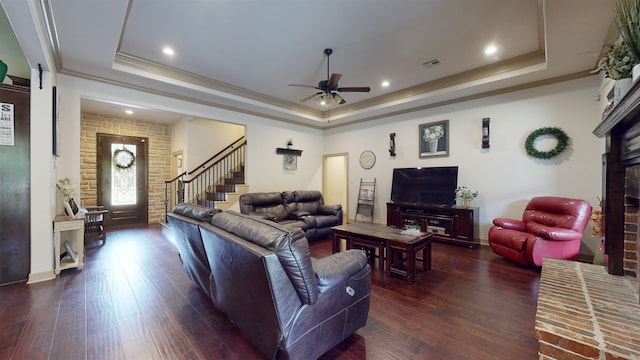 living room featuring a tray ceiling, dark wood-type flooring, and visible vents