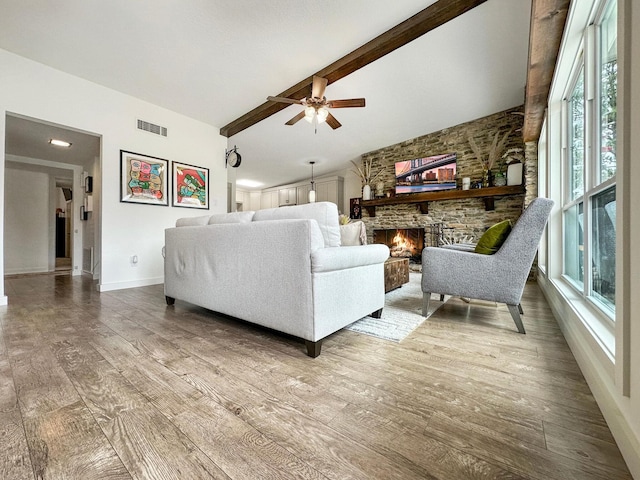 living room featuring a fireplace, vaulted ceiling with beams, visible vents, wood finished floors, and baseboards