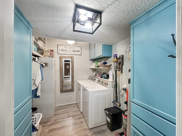 laundry area with a textured ceiling, separate washer and dryer, cabinet space, and light wood-style floors