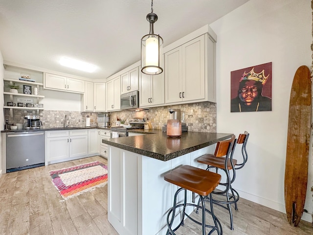 kitchen with decorative backsplash, appliances with stainless steel finishes, a peninsula, light wood-type flooring, and open shelves