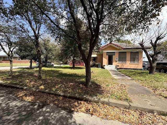 bungalow-style house featuring stucco siding, a tile roof, and a front yard