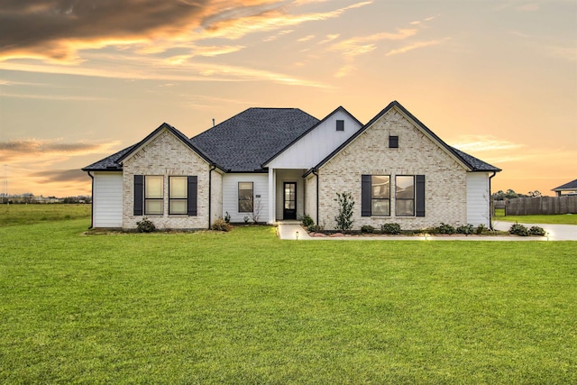 view of front of property with a front yard, brick siding, and fence