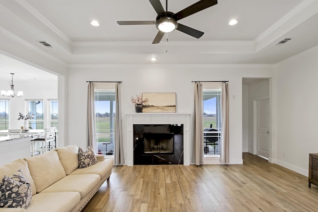 living area featuring light wood-type flooring, visible vents, a raised ceiling, and crown molding