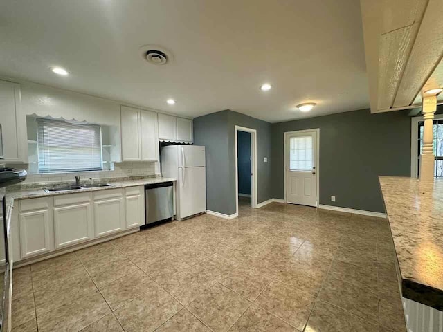 kitchen with light stone counters, stainless steel dishwasher, sink, white cabinets, and fridge