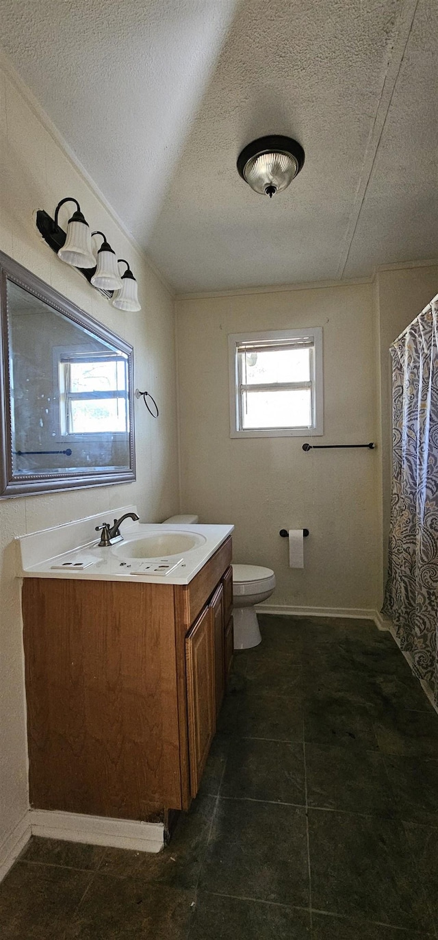 bathroom featuring vanity, a healthy amount of sunlight, a textured ceiling, and toilet