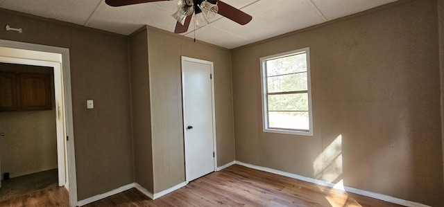 unfurnished bedroom with hardwood / wood-style flooring, ceiling fan, crown molding, and a closet