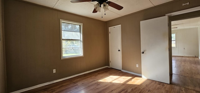 unfurnished bedroom with multiple windows, wood-type flooring, and ornamental molding