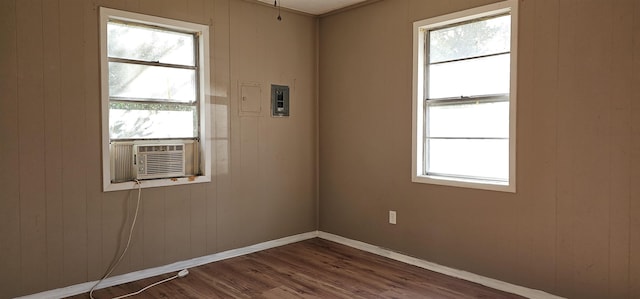 empty room featuring cooling unit, a wealth of natural light, and dark hardwood / wood-style floors