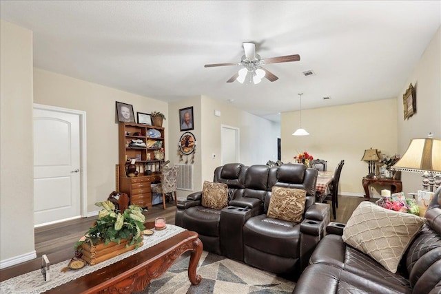 living area with a ceiling fan, visible vents, and wood finished floors