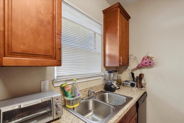 kitchen with brown cabinets, light countertops, a sink, and dishwasher