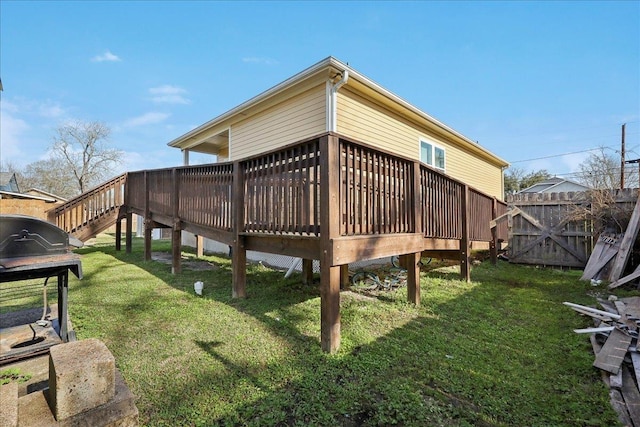 rear view of house featuring fence, a lawn, and a wooden deck