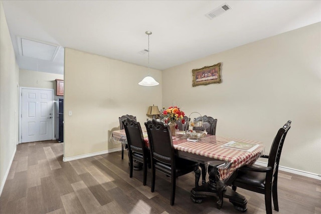 dining space with baseboards, attic access, visible vents, and wood finished floors