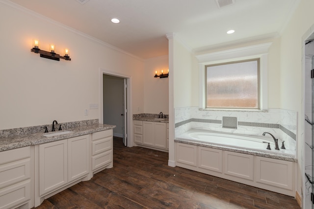 full bath with two vanities, ornamental molding, a sink, wood finished floors, and a bath