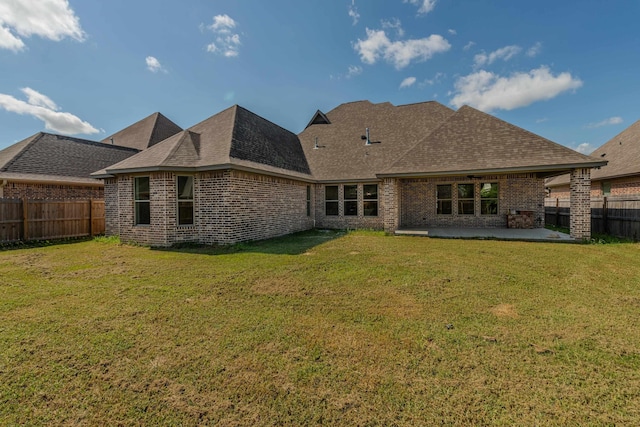 back of house with a yard, brick siding, and a fenced backyard