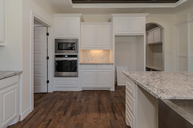 kitchen featuring decorative backsplash, dark wood-type flooring, light stone countertops, stainless steel appliances, and white cabinetry