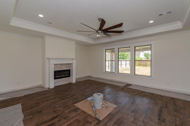 unfurnished living room with a tray ceiling, wood finished floors, and a glass covered fireplace