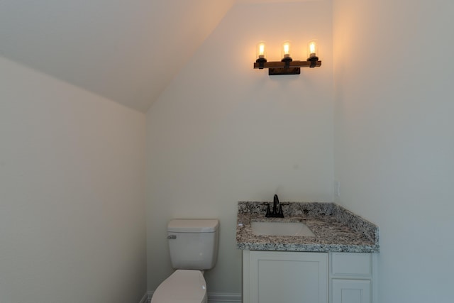 bathroom with lofted ceiling, vanity, and toilet