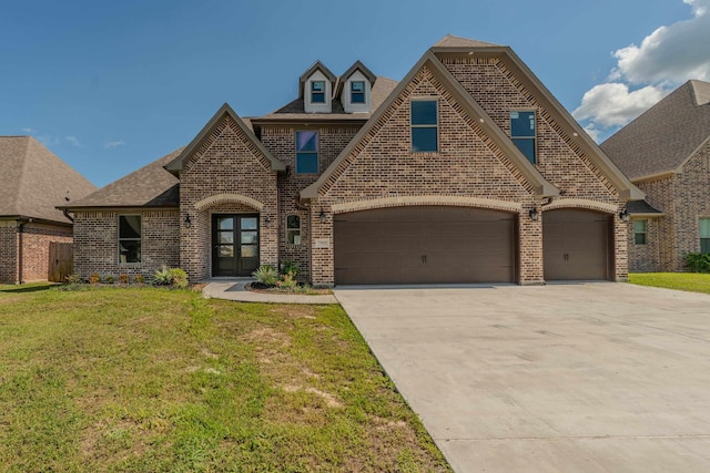 french provincial home featuring a garage, a front yard, concrete driveway, and brick siding