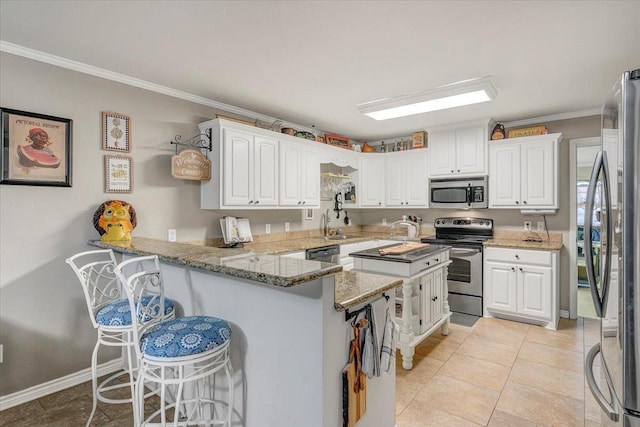 410 Christy Ln, Bridge City, TX 77611 - kitchen with appliances with stainless steel finishes, a kitchen breakfast bar, a peninsula, ornamental molding, and white cabinetry