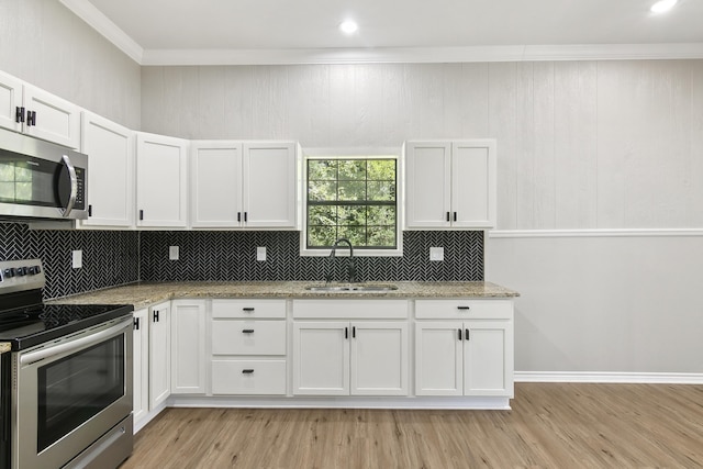 kitchen featuring stainless steel appliances, crown molding, a sink, and light stone countertops