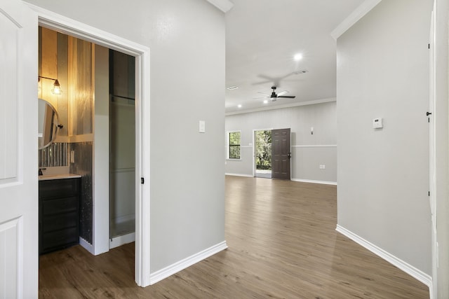 hall with baseboards, ornamental molding, and wood finished floors