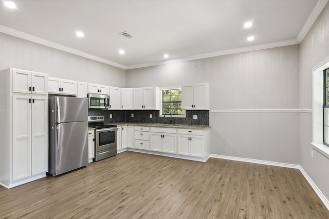 kitchen featuring visible vents, decorative backsplash, appliances with stainless steel finishes, white cabinets, and a sink