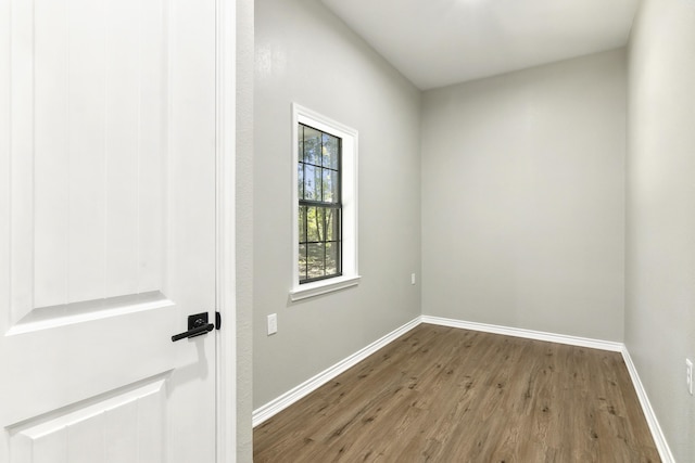 spare room featuring baseboards and wood finished floors