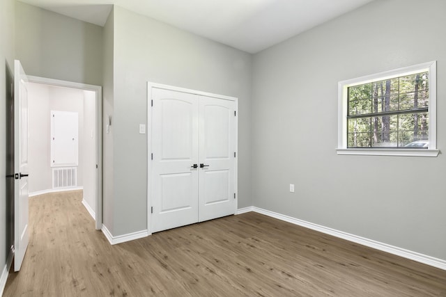 unfurnished bedroom featuring light wood-style floors, baseboards, visible vents, and a closet