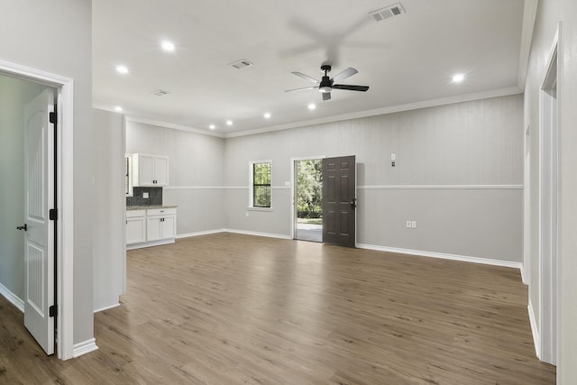 unfurnished living room with light wood-style floors, visible vents, and crown molding