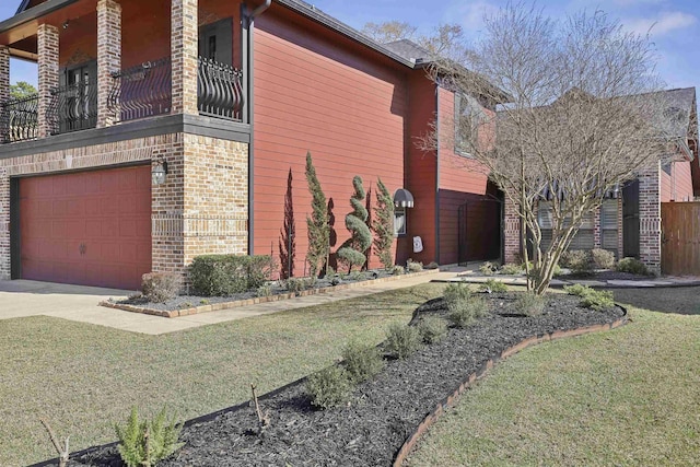 view of property exterior featuring a garage, brick siding, a yard, and a balcony