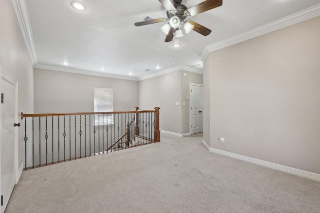 carpeted spare room featuring visible vents, baseboards, ceiling fan, and crown molding