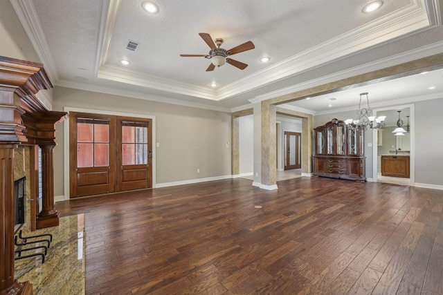 unfurnished living room featuring hardwood / wood-style flooring, a raised ceiling, visible vents, baseboards, and ceiling fan with notable chandelier