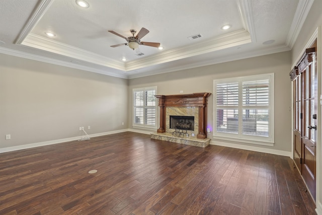 unfurnished living room with baseboards, a premium fireplace, a tray ceiling, and dark wood-type flooring