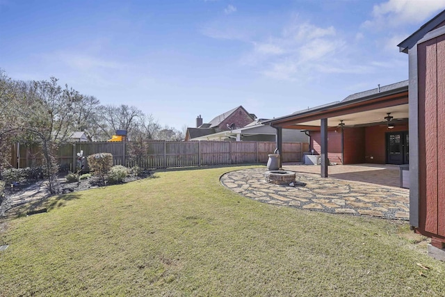 view of yard featuring an outdoor fire pit, a patio area, a fenced backyard, and a ceiling fan