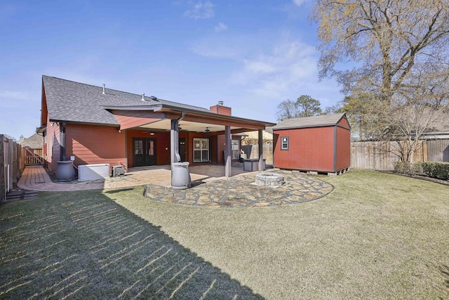 rear view of house featuring an outbuilding, a patio, a fenced backyard, a lawn, and a shed