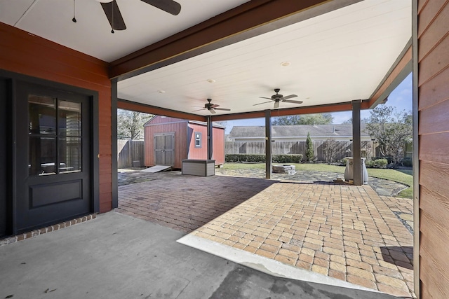 view of patio / terrace with a storage shed, ceiling fan, fence, and an outdoor structure