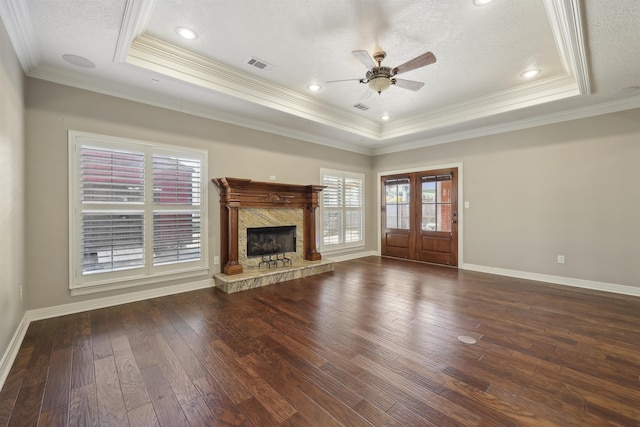 unfurnished living room featuring hardwood / wood-style floors, a tray ceiling, visible vents, and baseboards