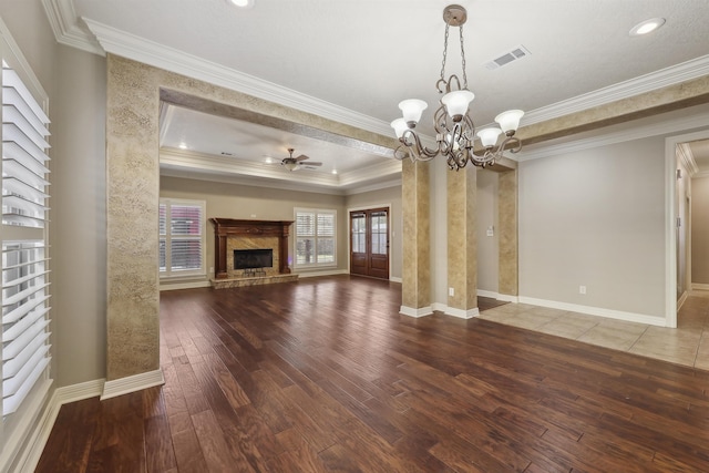 unfurnished living room featuring hardwood / wood-style flooring, visible vents, a premium fireplace, ornamental molding, and ceiling fan with notable chandelier