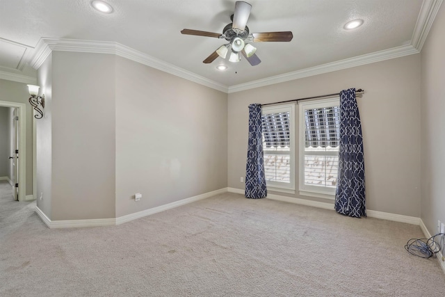 empty room featuring ornamental molding, attic access, carpet flooring, ceiling fan, and baseboards