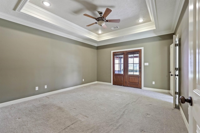 spare room with a tray ceiling, french doors, light colored carpet, visible vents, and baseboards