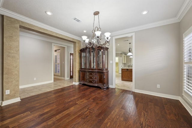 unfurnished dining area featuring visible vents, crown molding, and hardwood / wood-style flooring