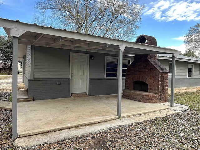 exterior space with an outdoor brick fireplace and a patio