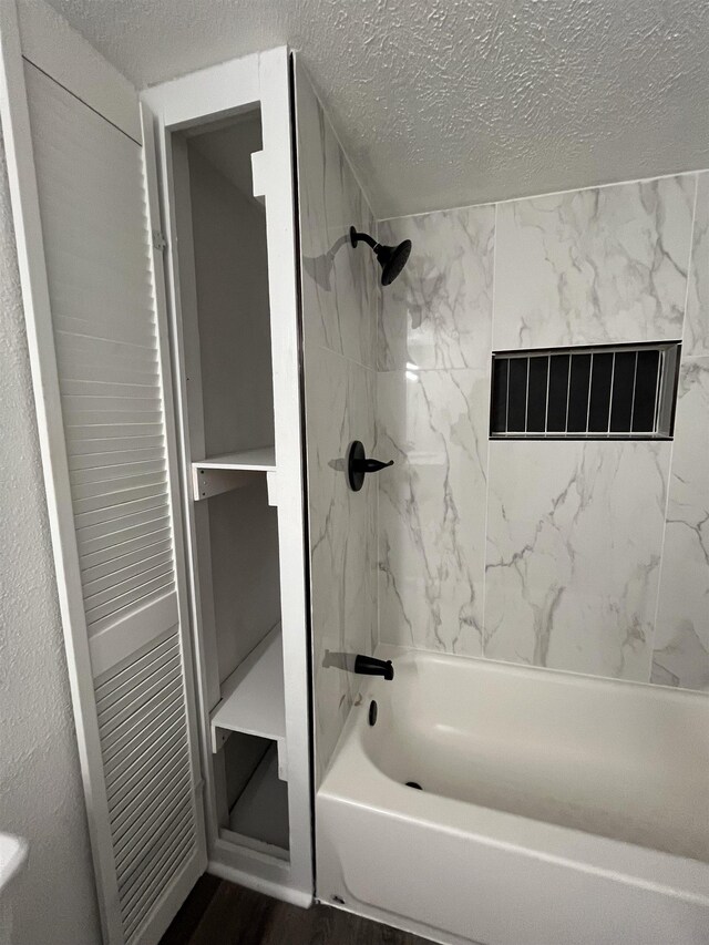 bathroom featuring tiled shower / bath combo, hardwood / wood-style floors, and a textured ceiling