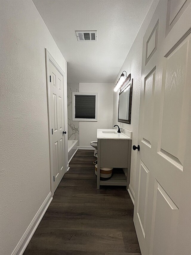 full bathroom with shower / bath combination, hardwood / wood-style floors, vanity, a textured ceiling, and toilet