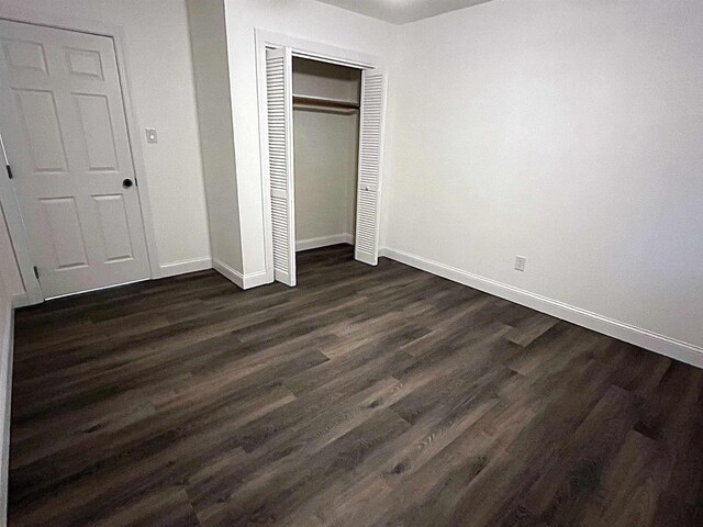 unfurnished bedroom with dark wood-type flooring and a closet